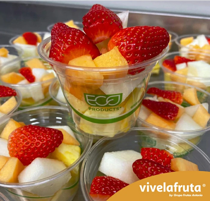 Una imagen en la que se ven muchos vasitos de plástico transparente con fruta fresca variada, en las que predominan las fresas.